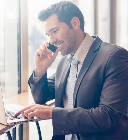 a man talking on the phone and looking at his laptop
