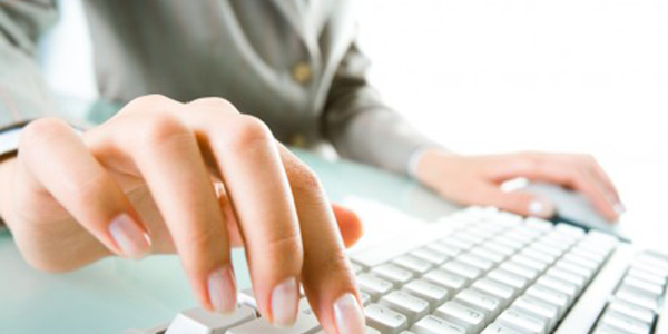 A woman's hand on a keyboard with a mouse.
